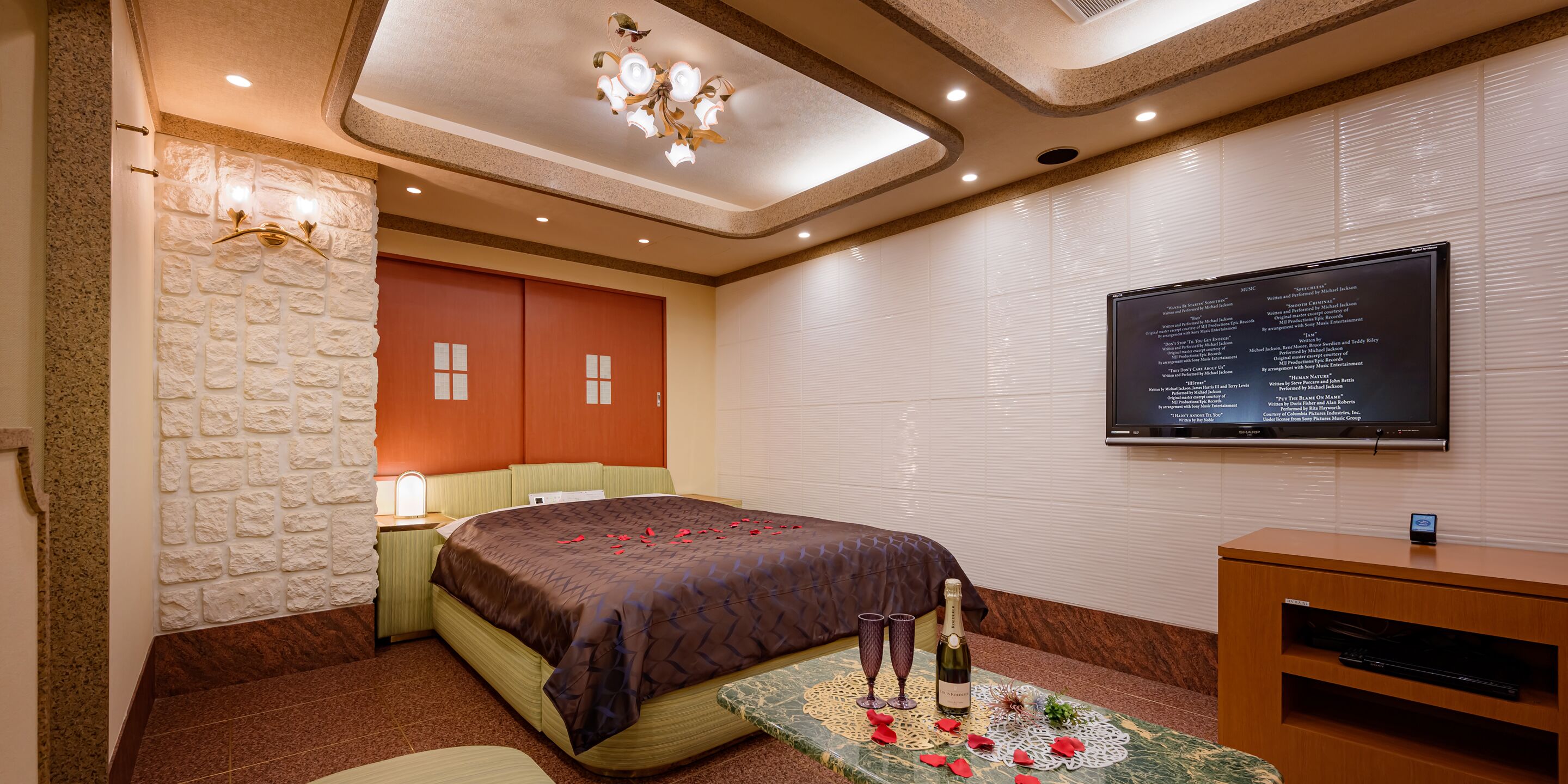 A hotel room with a bed, a television mounted on the wall, and a small wooden cabinet.