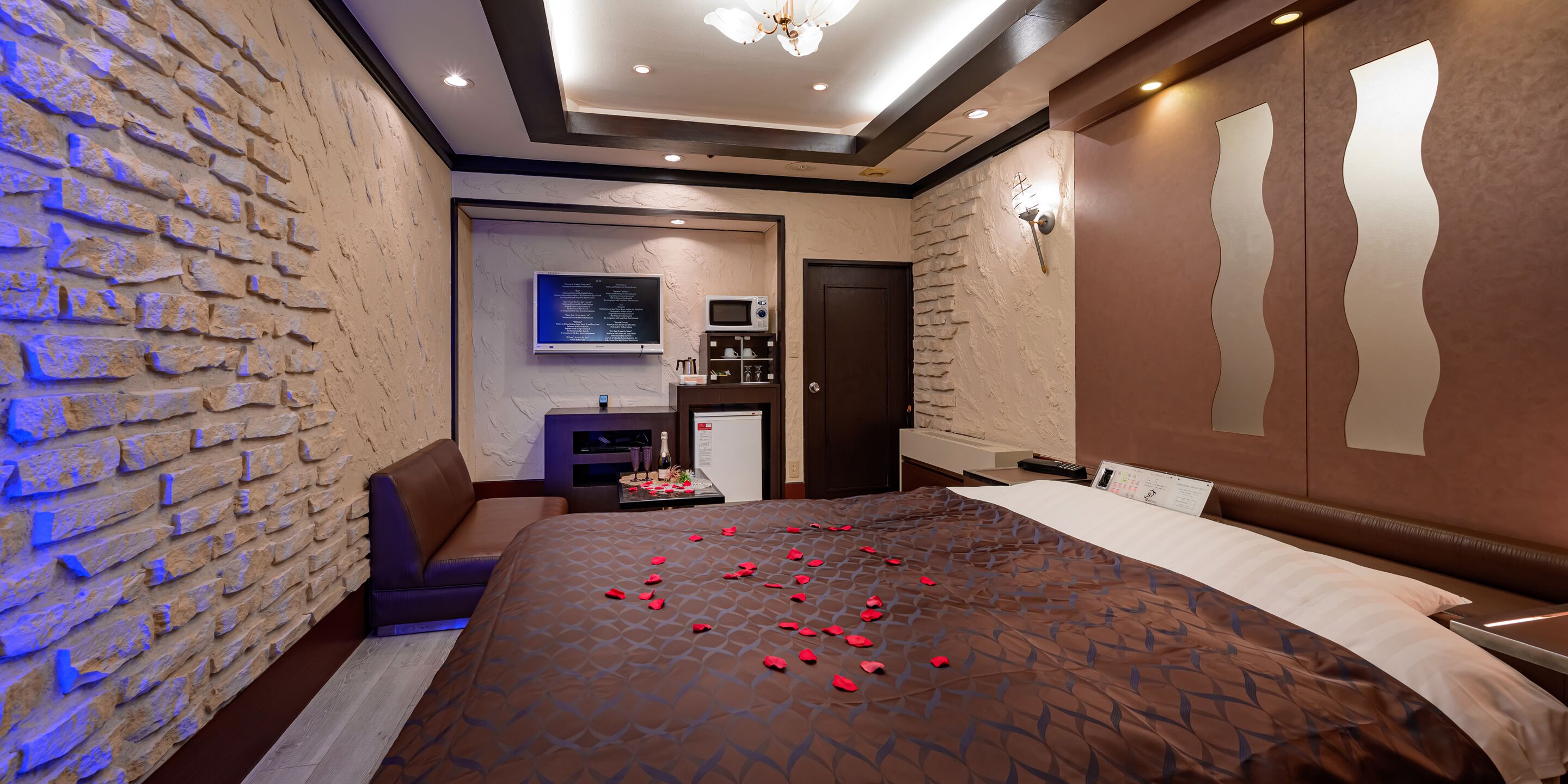 A hotel room with a bed, a TV, a minibar, and a bathroom.