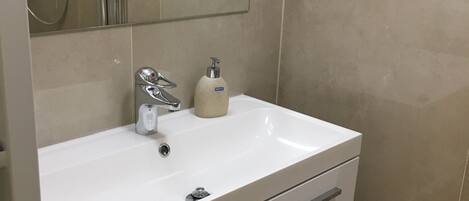 A bathroom with a white sink, a mirror, and a shower enclosure.