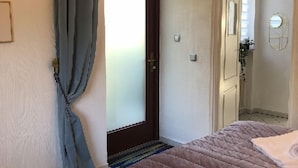 A bedroom with a bed, a door, and a mirror.