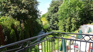 A balcony with a metal railing, potted plants, and a statue.