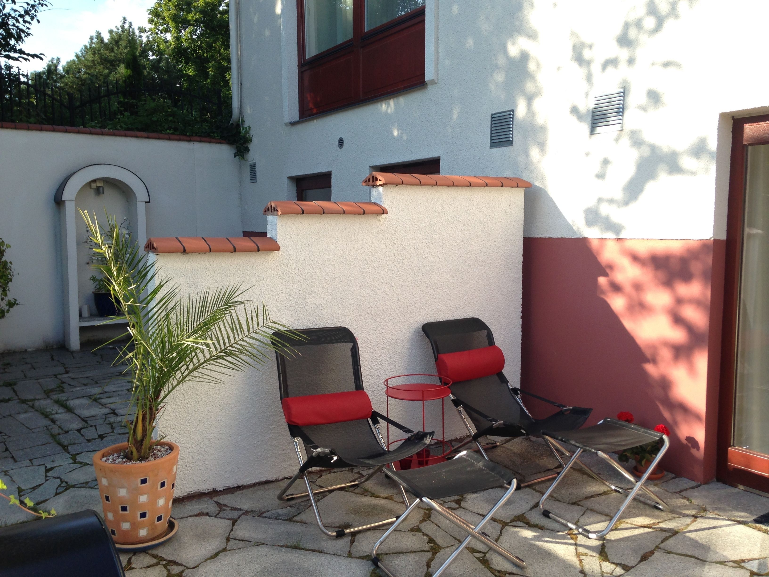 En terrasse med to liggestole, et lille bord og en potteplante.