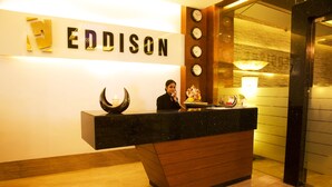A reception desk with a sign that reads "EDDISON" and a clock on the wall. - Eddison Hotel (Gurugram)