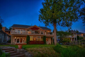 A two-story house with a balcony, a large tree in front, and a well-maintained lawn. - Lakefront Home-4 Bedrooms, 3 Full Bathrooms-Sleeps 10+ Hot Tub and Kayaks  (Bremerton)