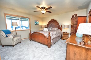A bedroom with a wooden bed, a chair, a dresser, and a ceiling fan. - Lakefront Home-4 Bedrooms, 3 Full Bathrooms-Sleeps 10+ Hot Tub and Kayaks  (Bremerton)
