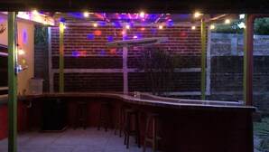 Un espace bar avec un mur en briques servant de décor, illuminé par des guirlandes lumineuses colorées.