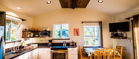 A kitchen with white cabinets, stainless steel appliances, and a dining area with wooden chairs and a table.