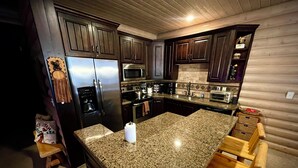 Una cocina con armarios de madera oscura, electrodomésticos de acero inoxidable y encimera de granito.