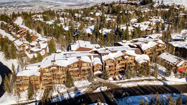 Un resort cubierto de nieve con varios edificios, incluyendo un gran lodge con balcones y un telesilla visible al fondo.