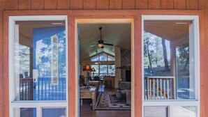 A wooden cabin with a porch, a ceiling fan, and a view of the surrounding forest. - Tucked Away Cabin | Quiet Forest Haven w/ Hot Tub Deck (Ruidoso)