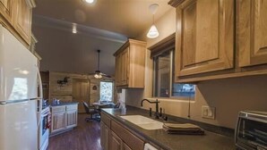 A kitchen with wooden cabinets, a white refrigerator, a sink, and a stove. - Tucked Away Cabin | Quiet Forest Haven w/ Hot Tub Deck (Ruidoso)