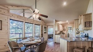 A spacious kitchen with wooden cabinets, a central island, and large windows offering views of the outdoors. - Tucked Away Cabin | Quiet Forest Haven w/ Hot Tub Deck (Ruidoso)