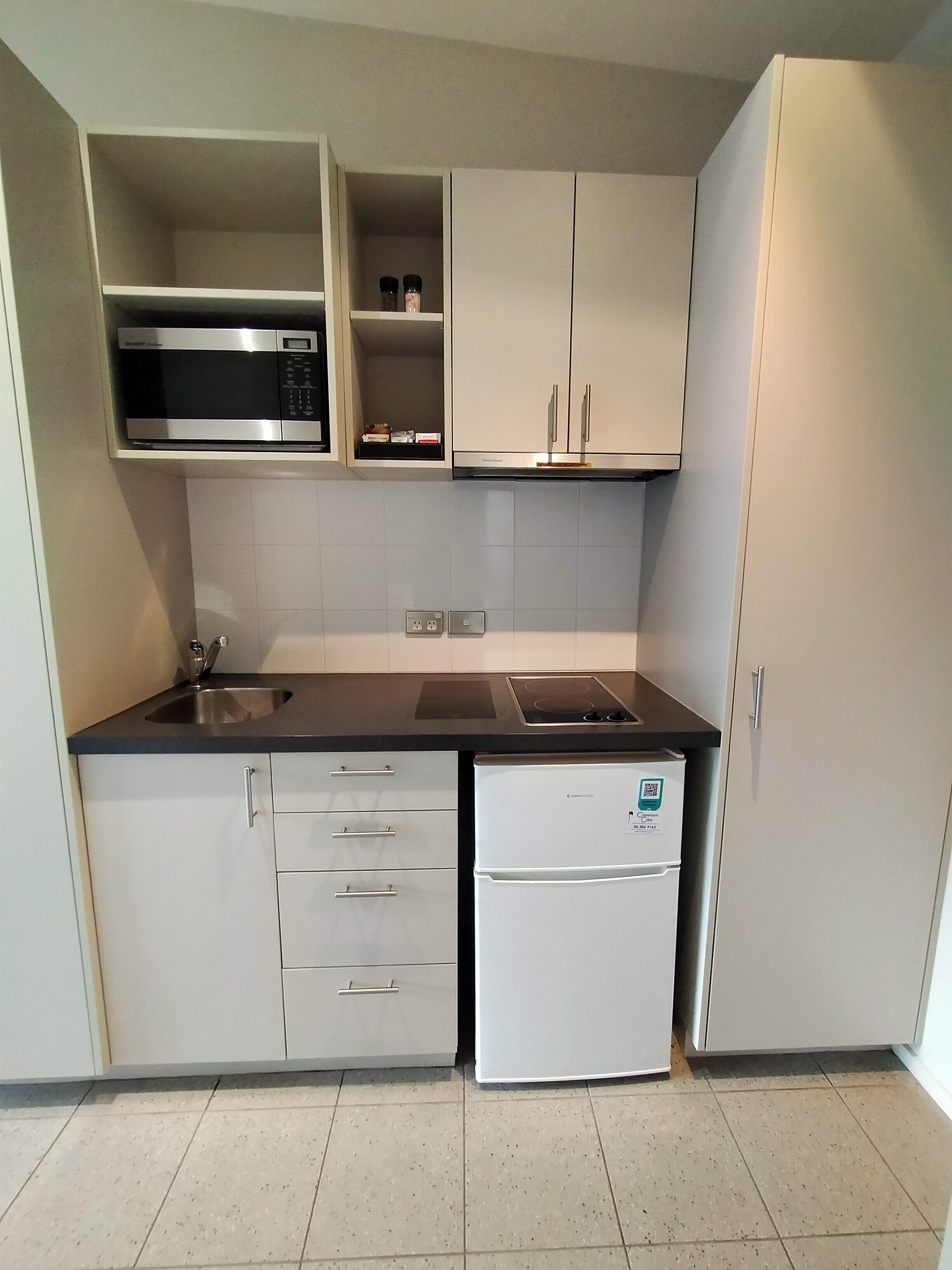 A compact kitchen with a microwave, stove, sink, and a refrigerator.