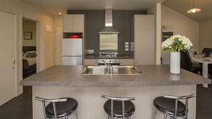 Uma cozinha moderna com ilha central, eletrodomésticos de aço inoxidável e banquetas.