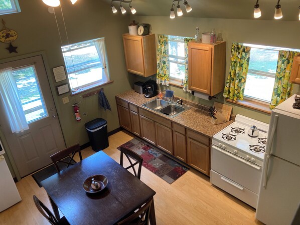 A compact kitchen with wooden cabinets, a stove, and a sink.