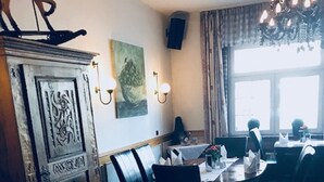 Interior de un restaurante con un aparador de madera, mesas, sillas y una araña.