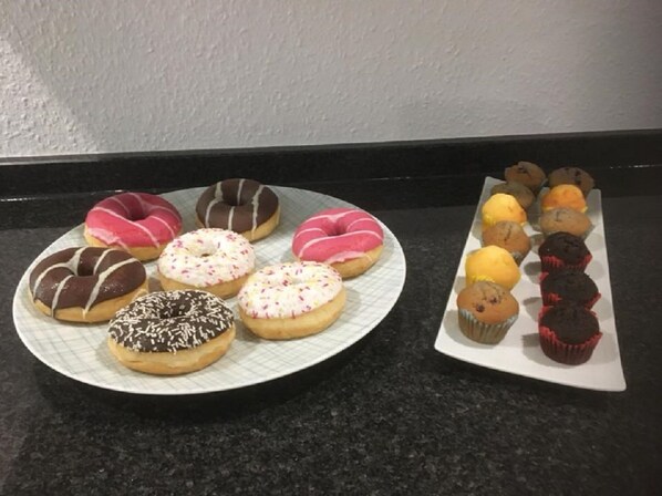 A plate of assorted donuts and cupcakes on a kitchen counter.