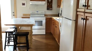 Una cocina con armarios de madera, una estufa blanca y un refrigerador.