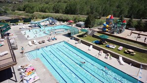 Un espace piscine comprenant plusieurs couloirs de nage, un toboggan et une aire de jeux.