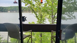 Un balcón con dos sillas, vista a un lago y comederos para pájaros colgantes.