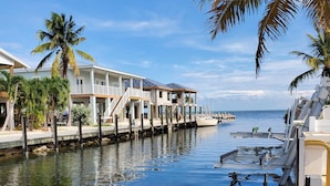 Ein Anwesen am Wasserufer mit Anlegesteg, einem Boot und einem Gebäude mit Balkon.