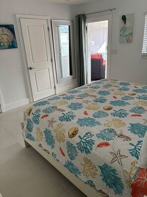 A bedroom with a bed, a door, and a view of the outside. - Ocean Side Canal Half Duplex, 37' Dock, 600' To Channel With Pool (Marathon)