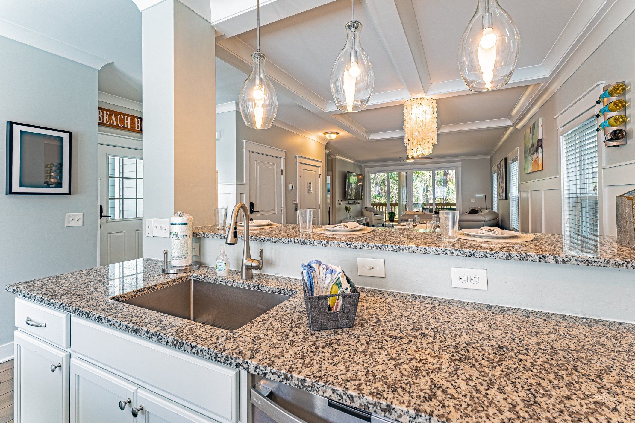 A kitchen with granite countertops, a stainless steel sink, and pendant lighting.