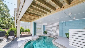 An indoor swimming pool with a wooden ceiling, a seating area with a sofa and chairs, and a view of the outdoors. - 117 Heated Pool | Elevator | Kids Retreat | Sleeps Big Families | Pet Friendly (Hilton Head Island)
