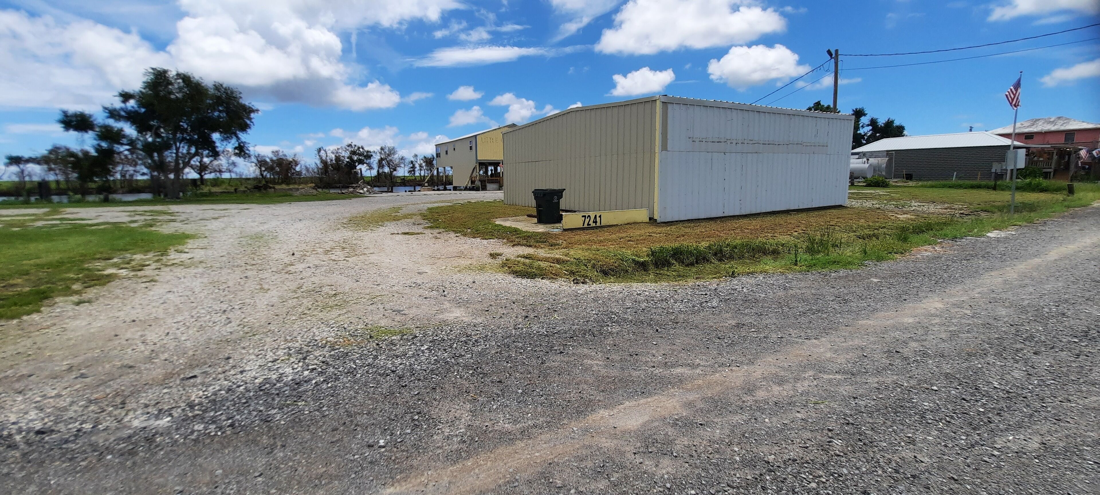A gravel road leading to a small industrial building with a number '7241' on the side.