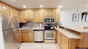 A kitchen with wooden cabinets, stainless steel appliances, a granite countertop, and a tiled floor. - Terracehouse - Steps to Slopes - Hot Tub/Pool - ASE Transportation (Snowmass Village)