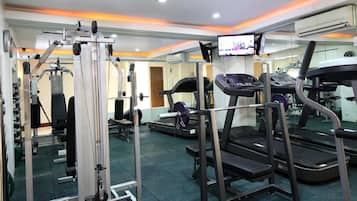 Un gimnasio con diversos equipos de ejercicio, incluyendo cintas de correr, un banco de pesas y una estructura para sentadillas.
