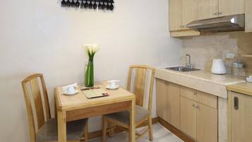 Una cocina pequeña con armarios de madera, un lavamanos y una mesa de comedor con sillas.
