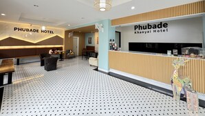 Zona de recepción de hotel con diseño moderno, que incluye un mostrador de recepción, área de estar y un piso con diseño.