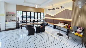 Un vestíbulo de hotel con una zona de estar, un ventilador de pared y un cartel que dice 'PHUBADE HOTEL'.