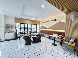 A hotel lobby with a seating area, a wall-mounted fan, and a banner reading 'PHUBADE HOTEL'. - New Phubade Khaoyai hotel (Pak Chong)