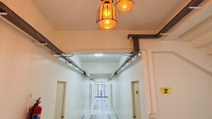 Pasillo de hotel con extintor, cartel de número y alfombra estampada.