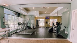 A gym with exercise equipment, a large window, and a mirror.