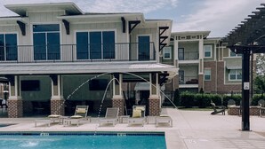 A swimming pool with lounge chairs and a building with multiple balconies in the background.