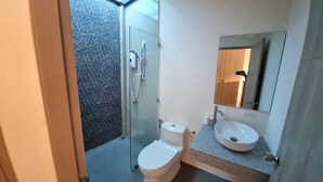Un baño moderno con cabina de ducha de vidrio, inodoro blanco y lavamanos con un espejo grande colgando sobre él.