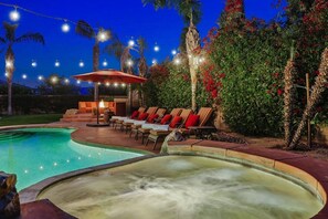 A swimming pool area with lounge chairs and an umbrella, surrounded by lush greenery and palm trees. - Acacia: Pool, Spa, Fire Pit, Sauna, Poker, Arcade (Indio)