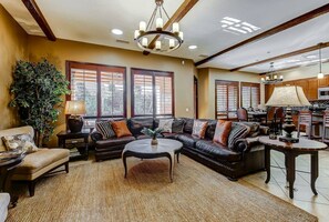 A living room with a sectional sofa, a coffee table, and a chandelier.