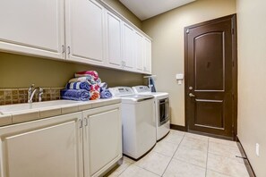 A laundry area with a washing machine, stacked towels, and a sink.