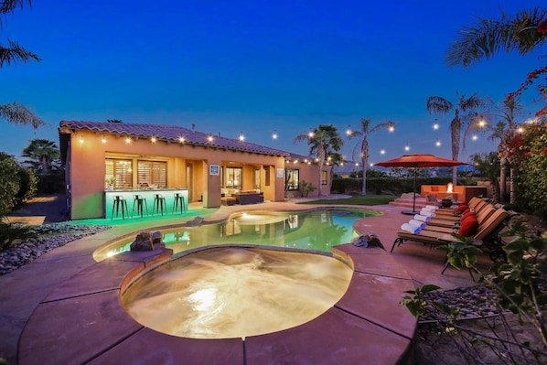 A residential property with a swimming pool, outdoor seating, and a bar area.