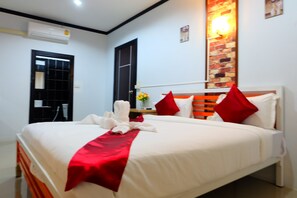 A neatly made bed with white and red bedding, a black door, and a brick accent wall. - Yenta Resort (Chumphon)