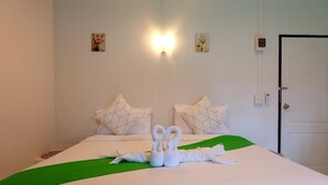 A neatly made bed with a green bedspread, two pillows with geometric patterns, and a swan-shaped towel arrangement. - Yenta Resort (Chumphon)