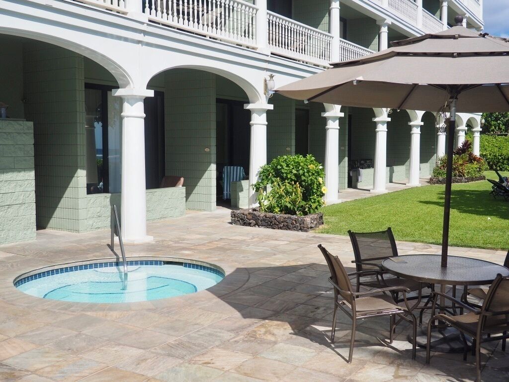 Ein Poolbereich mit Whirlpool, Sitzgelegenheiten im Freien und einer überdachten Terrasse.