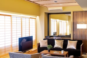 Uma sala de estar moderna com sofá, televisão e uma mesinha com uma planta.