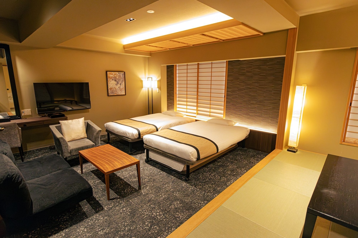 Une chambre d’hôtel avec deux lits, un bureau, une chaise et un téléviseur.