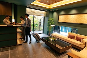 Un hall d’hôtel comprenant un comptoir d’accueil, un canapé, une table basse et une plante en pot.