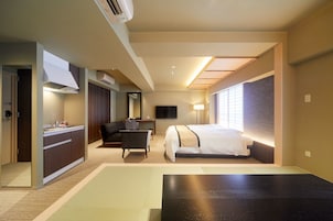 A hotel room with a bed, a desk, a chair, a TV, and a window with blinds.